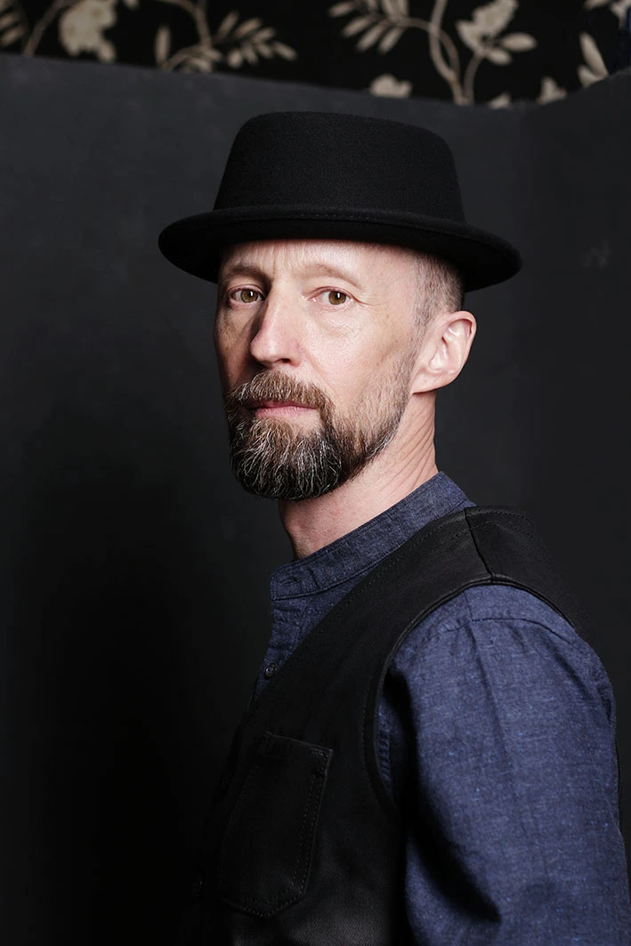 Fotostudio Dortmund Portraitfotografie Mann mit Hut vor dunklem Hintergrund